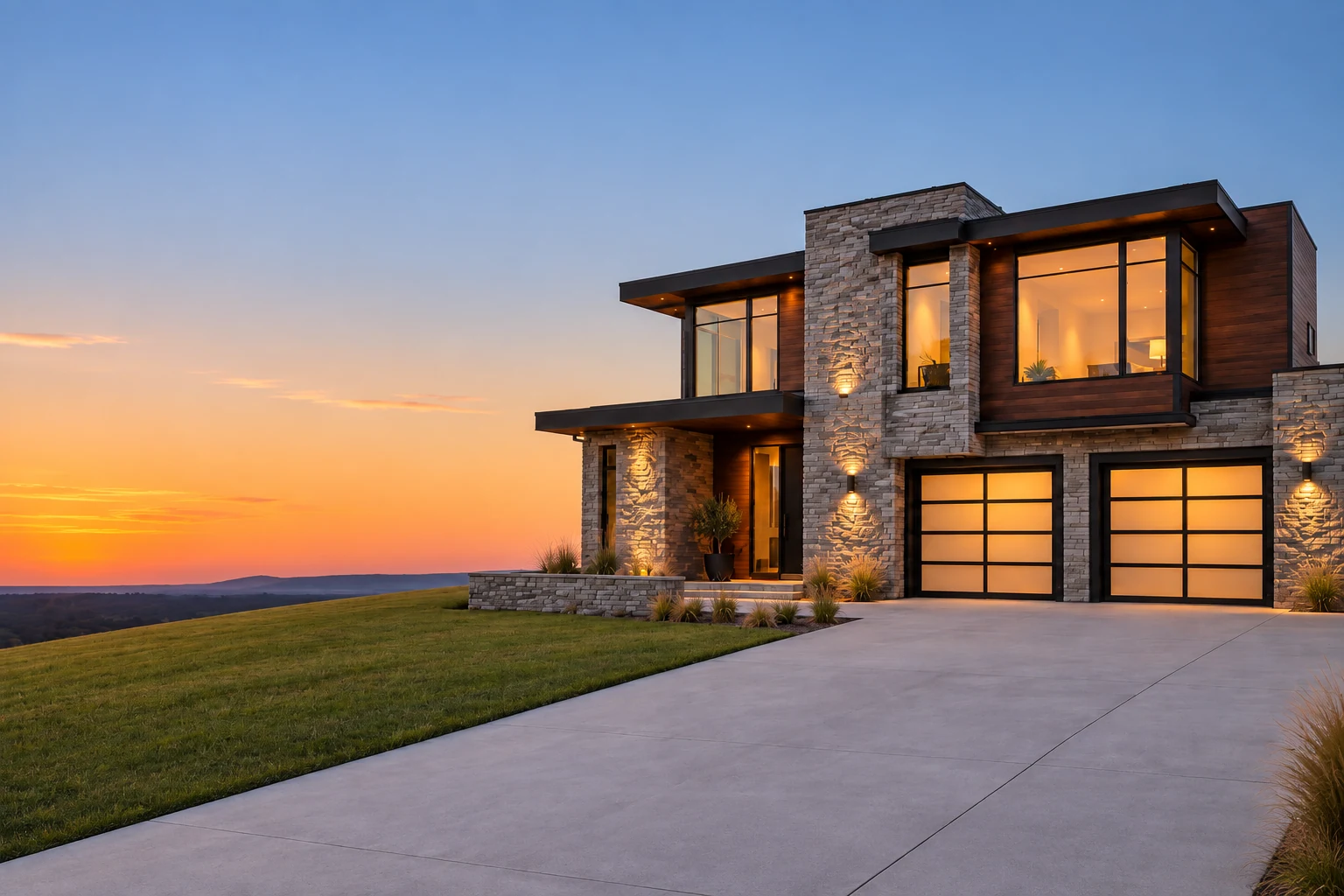 Contemporary stone home with warm interior lighting at sunset